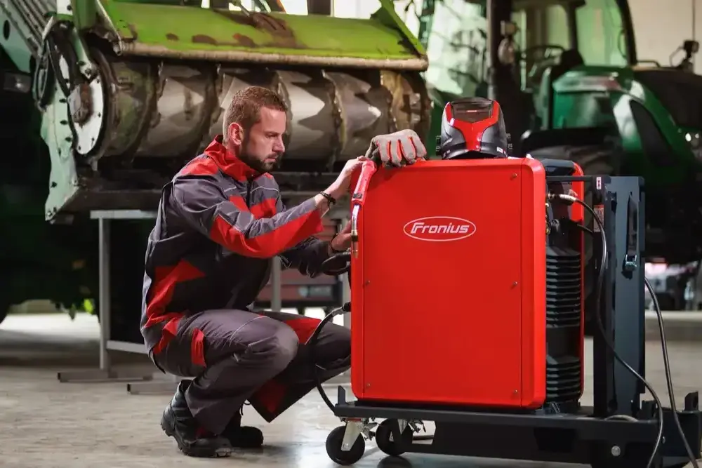 Сварщик настраивает аппарат Fronius Fortis в промышленной мастерской